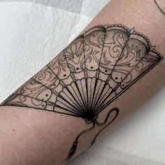 a black and white photo of a fan tattoo on the arm