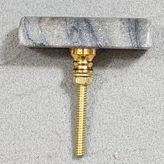 a marbled metal hook with a screw on it's end and a gold - plated handle