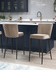 two chairs sitting in front of a kitchen island with marble counter tops and blue cabinets