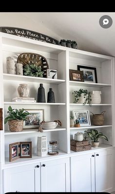 a white bookcase filled with lots of books and vases on top of it