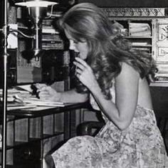 a woman sitting at a desk in front of a lamp