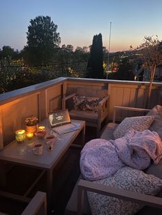 an outdoor patio with two couches, table and candles on the deck at night