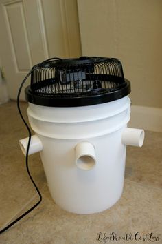 a white bucket with a black ventilator attached to it on a tile floor