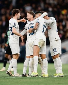 three soccer players are congratulating each other on the field