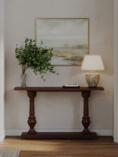 there is a plant on the table in front of the lamp and framed painting above it