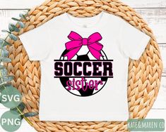 a white shirt with the word soccer sister on it and a pink bow is sitting next to a wicker basket