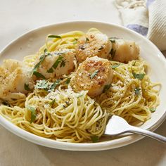 pasta with scallops and parmesan cheese in a white bowl on a table