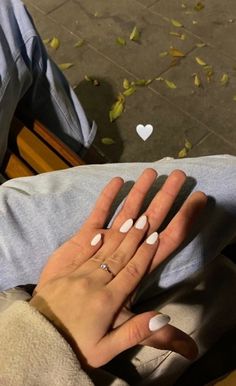 a woman's hand with white manicures and a heart - shaped ring