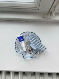 a hair comb and pearl necklace sitting on top of a window sill next to a white radiator