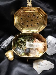 an open gold box filled with lots of different things next to some rocks and crystals