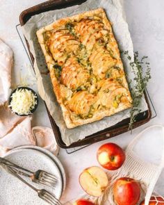 an apple pie is on a baking sheet next to some apples and other food items