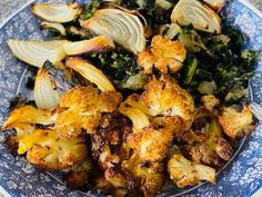 a blue and white plate topped with broccoli florets and cauliflower