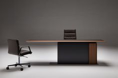 an office desk with a chair next to it in front of a gray wall and floor