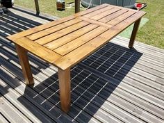 a wooden table sitting on top of a wooden deck next to a grass covered field