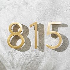 the number eighty five is placed in front of a white wall with gold numbers on it