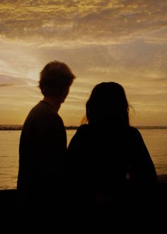 two people are looking out at the water