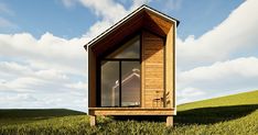 a small wooden cabin sitting on top of a lush green field next to a blue sky