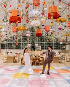 a bride and groom dancing in a large room with chandeliers hanging from the ceiling