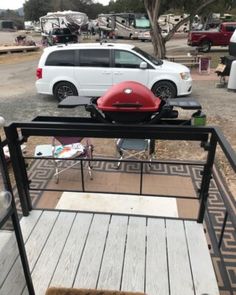 an rv park with cars parked in the parking lot and a grill on the deck