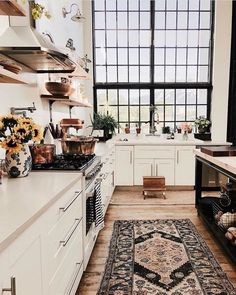 a kitchen filled with white cabinets and lots of counter space next to a large window