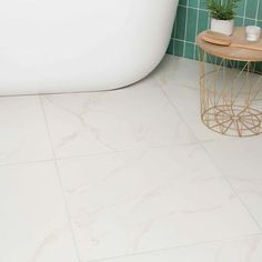 a white bath tub sitting next to a green tiled wall and floor in a bathroom