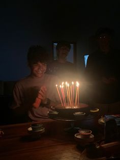 two people standing in front of a cake with lit candles