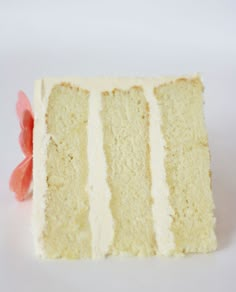 a piece of cake with white frosting and pink flowers on the top, sitting in front of a white background