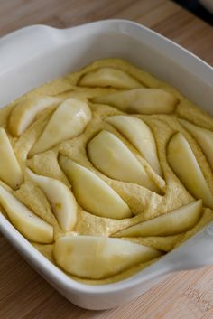 a white dish filled with sliced apples on top of a wooden table