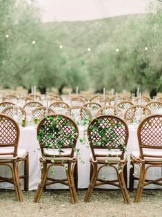 an outdoor wedding reception set up with white table cloths and chairs covered in greenery