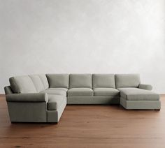 a large sectional couch sitting on top of a wooden floor next to a white wall