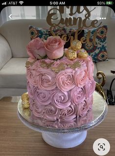 a pink and gold cake sitting on top of a wooden table next to a couch