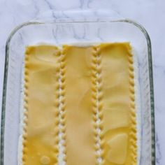 an uncooked pasta in a glass dish on a marble counter top with white trim