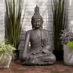 a buddha statue sitting in front of some plants