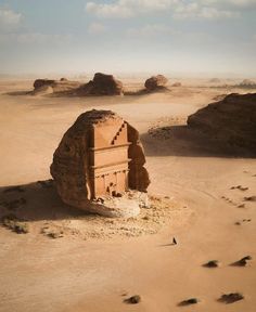 an old building in the middle of desert with rocks and sand around it, on a sunny day