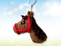 a crocheted horse keychain hanging from a hook on a blue and green background