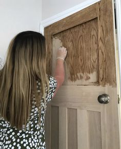 a woman is painting the front door of her house with brown paint and white flowers