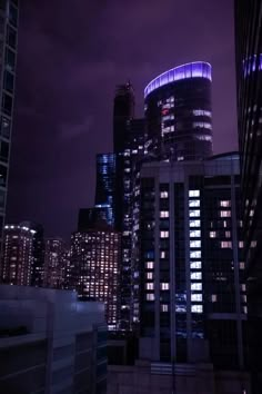 the city skyline is lit up at night with purple lights and skyscrapers in the background