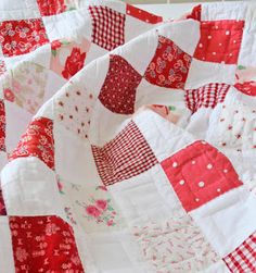 a red and white quilt is laying on top of a tablecloth with polka dots