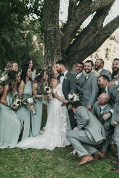 a group of people standing around each other in front of a tree and grass field