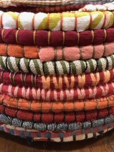 a stack of different colored cloths sitting on top of a wooden table