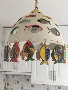 a light fixture hanging from the ceiling in a kitchen with fish painted on it's sides