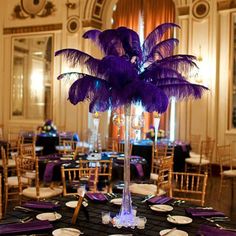 a tall centerpiece with purple feathers on it