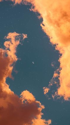 the moon is shining in the sky above some clouds and an orange glow on it