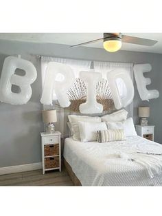 a bed with white sheets and pillows in a room that has balloons on the wall