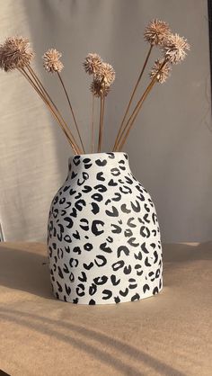 a white and black vase with flowers in it