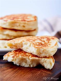 three pancakes stacked on top of each other on a white plate next to a wooden cutting board