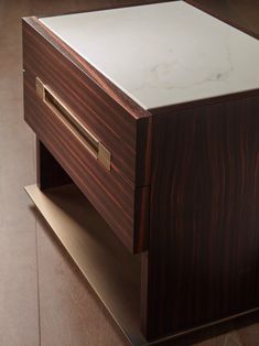 a wooden table with a white top and drawers on the bottom, sitting on a hard wood floor