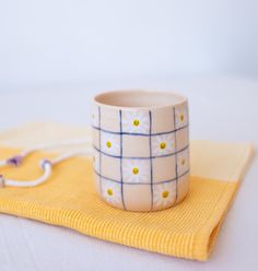 a cup sitting on top of a yellow towel next to a white and blue object