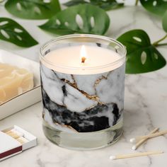 a white candle sitting on top of a table next to a box of matches and some green leaves