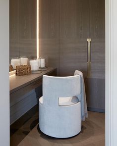 a white chair sitting on top of a wooden floor next to a table with candles